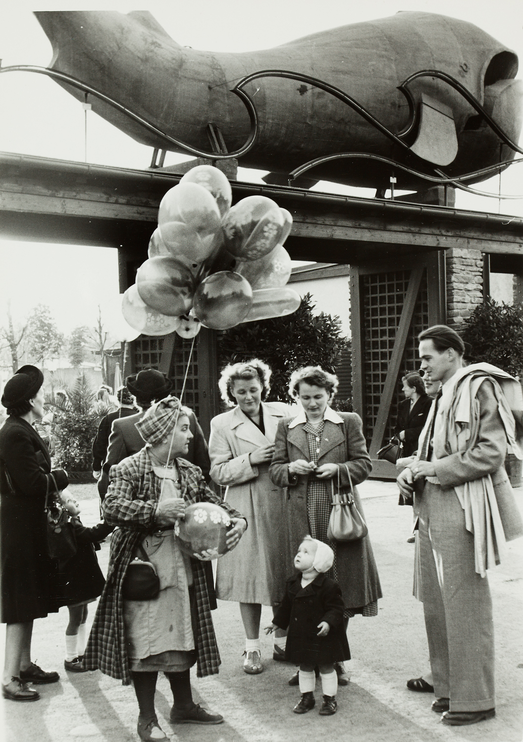 Foto mit Menschen rund um eine Luftballonverkäuferin, vor dem Gasthaus "Zum Walfisch" im Prater 