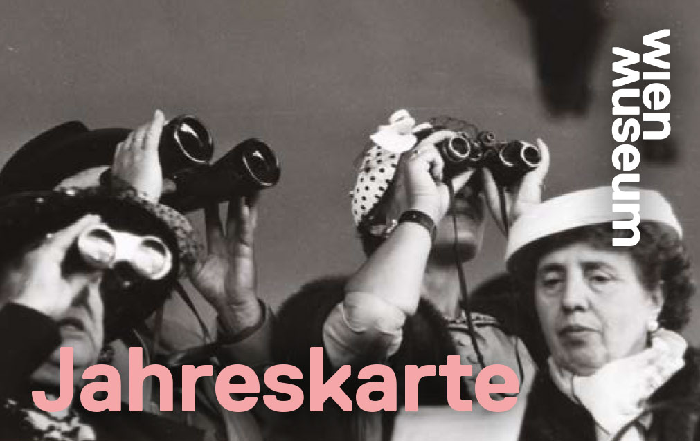 Frauen auf einer Tribüne schauen durch ein Fernglas ein Pferderennen. 