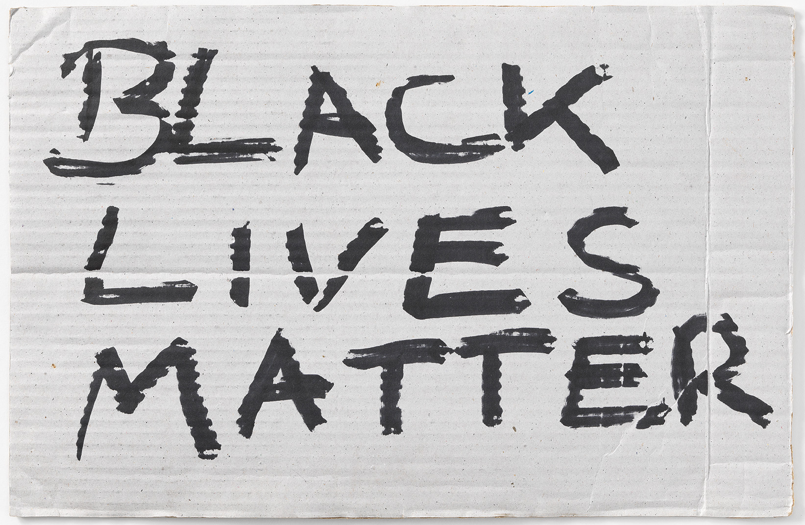 Ein Schild aus Karton mit schwarzer Aufschrift "Black lives matter"