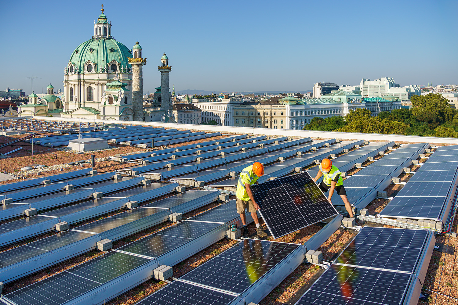 Zwei Männer montieren die Panele auf dem Dach des Museums. Im Hintergrund ist die Karlskirche zu sehen