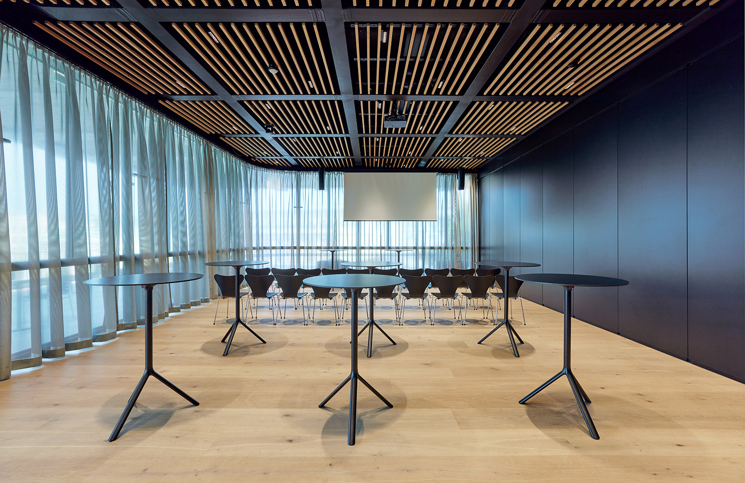 Einblick in den kleinen Saal, bestuhlt, mit Stehtischen und Leinwand