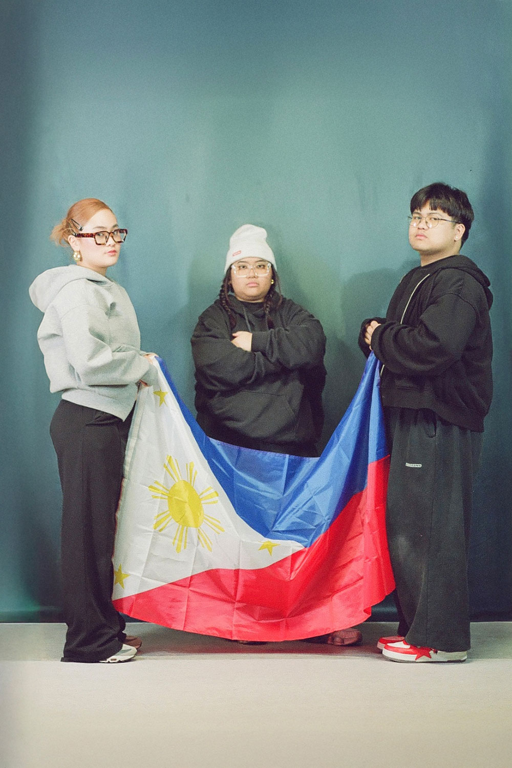 Drei Personen halten eine philippinische Flagge