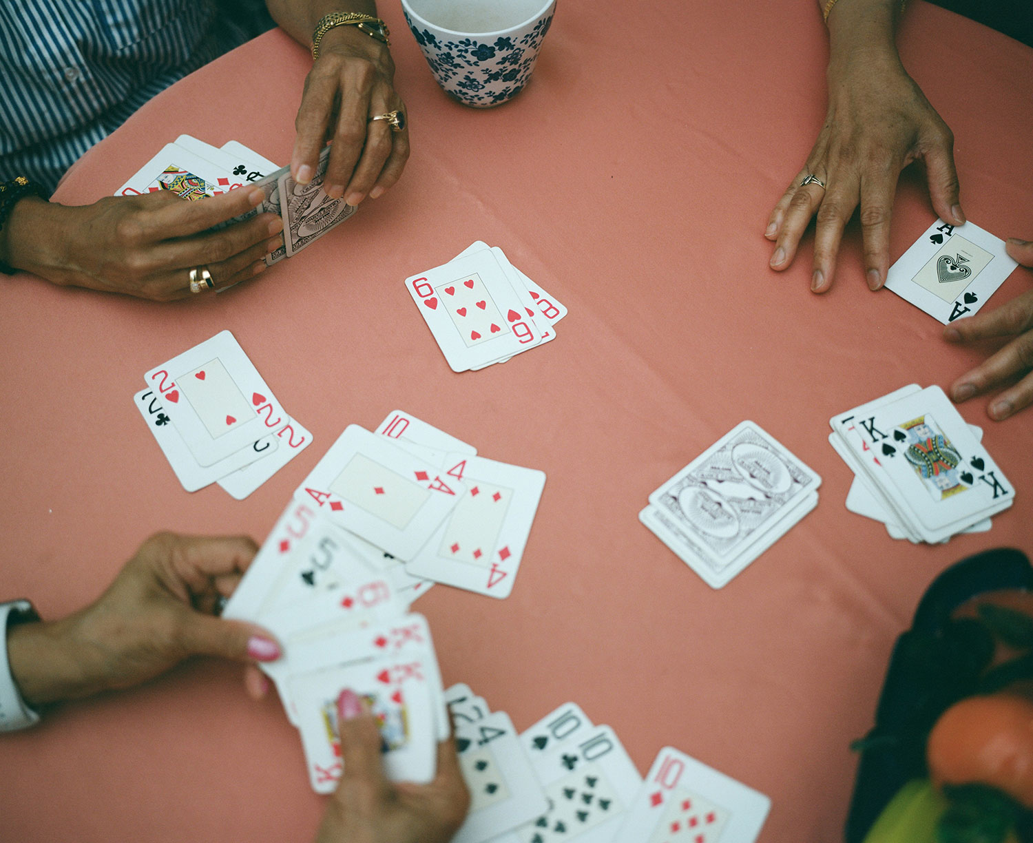 Spielkarten in Händen gehalten und auf einem Tisch liegend