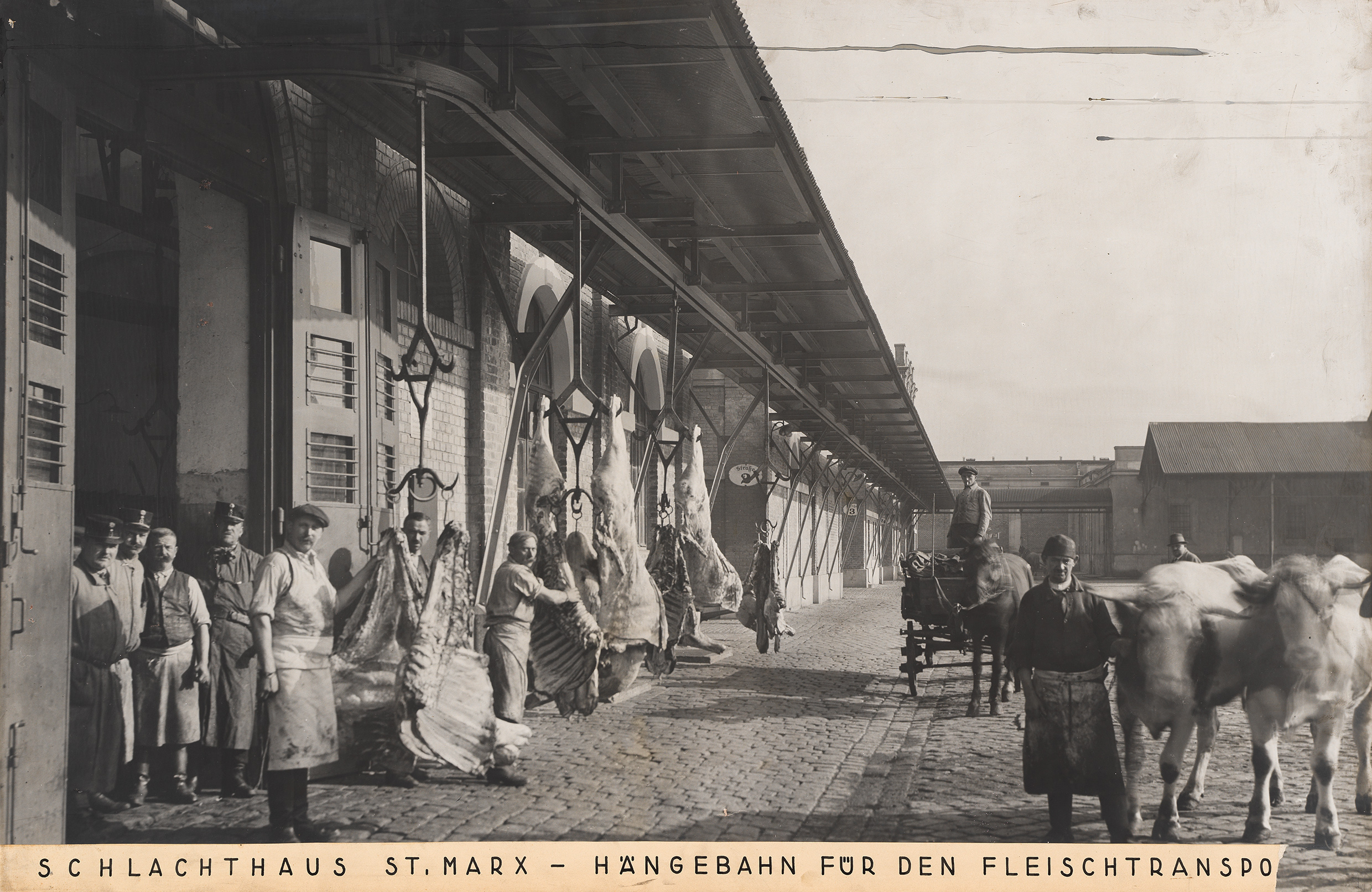 Menschen vor dem Schlachthof mit Fleischteilen und davor wartenden Kutschen zum Abtransport