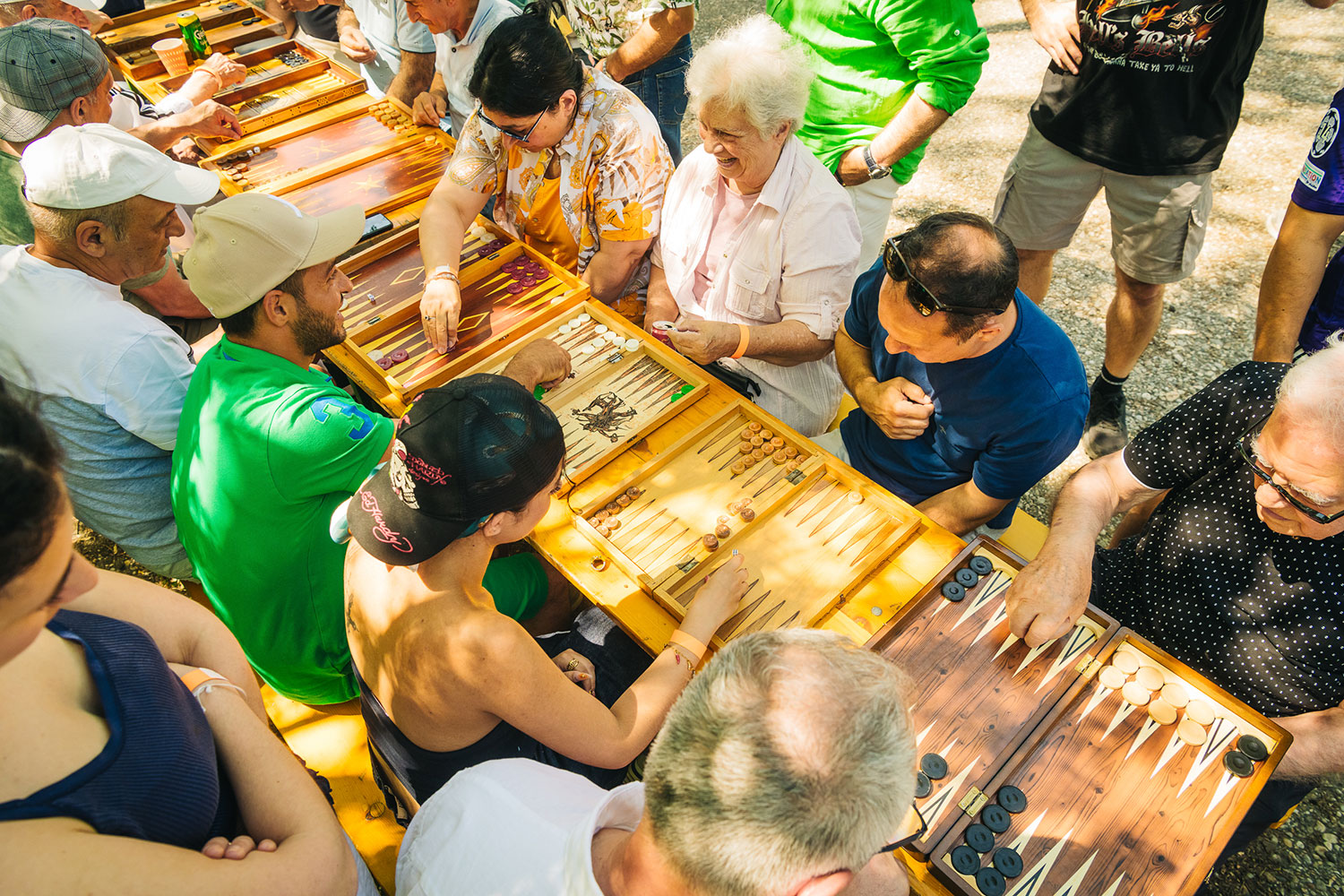 Frauen und Männer spielen an einem langen Tisch mit vielen Brettspielen 