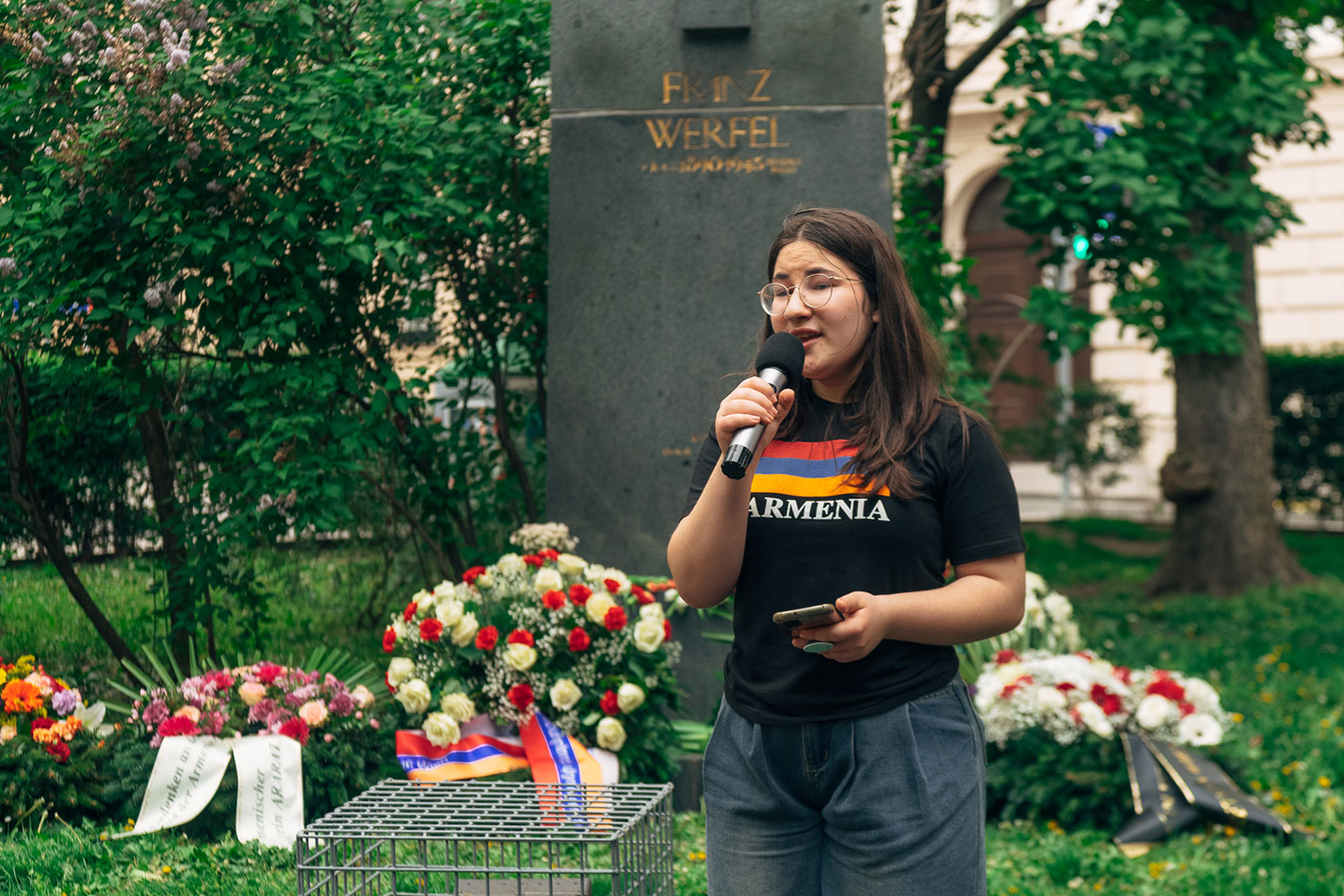 Junge Frau vor dem Denkmal von Franz Werfel mit vielen Blumenkränzen