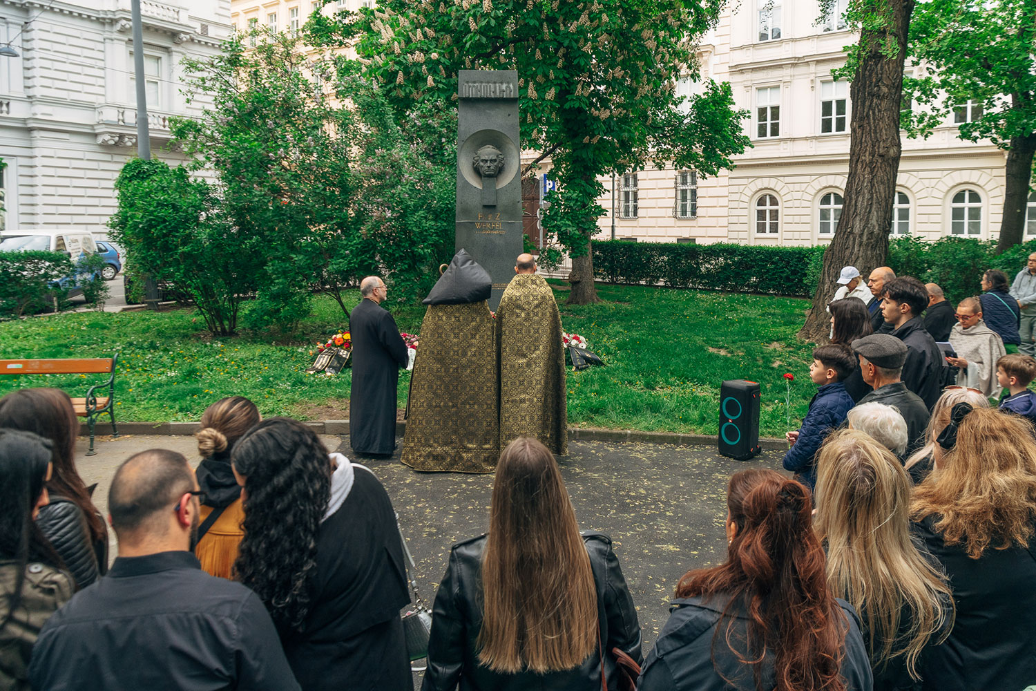 Geistliche und andere Menschen vor dem Denkmal von Franz Werfel