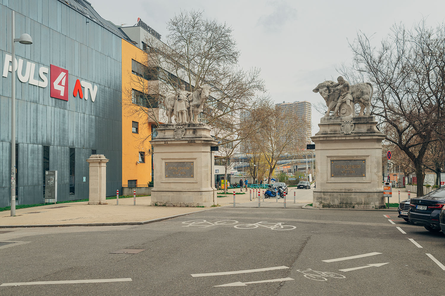 Portal mit zwei Sockel auf denen sich jeweils Statuen von einer Person mit einem Stier befinden