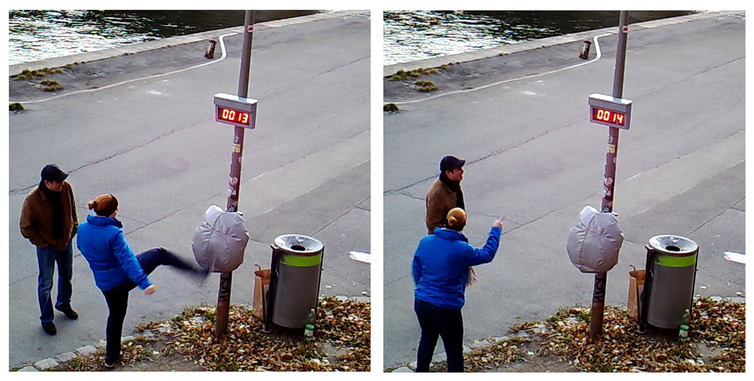 An einer Straßenlaterne hängt eine Art Boxsack und einem Messgerät, eine Frau tritt mit dem Fuß gegen den Sack und zeigt auf dem zweiten Still mit dem Finger auf das Ergebnis  um es dem Begleiter zu veranschaulichen 