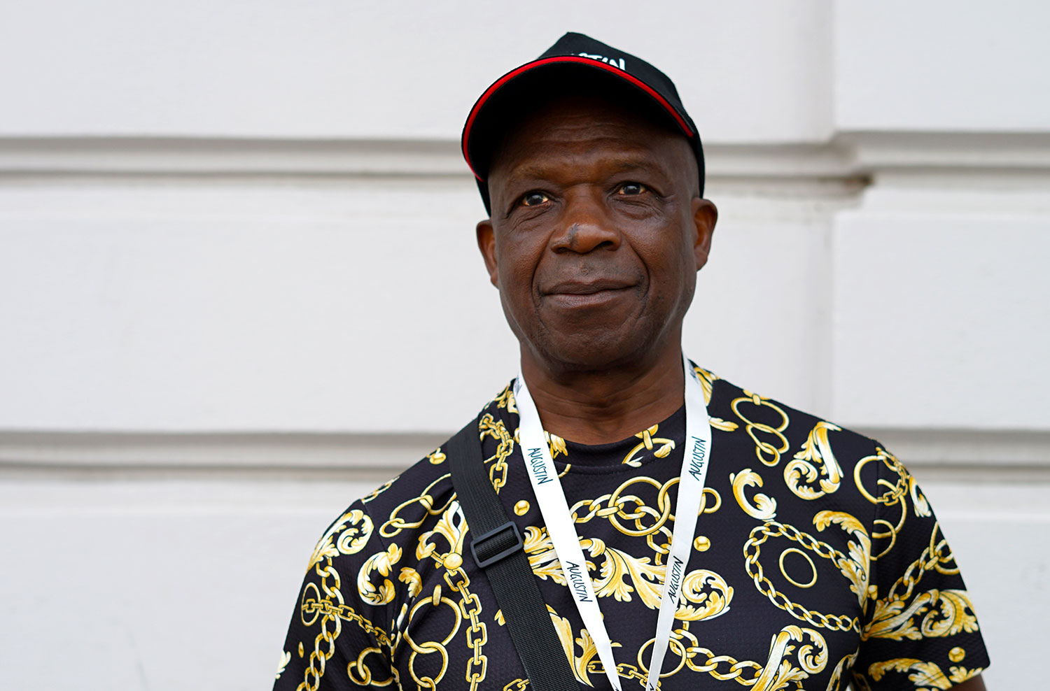 Augustin Verkäufer mit einer Kappe und einem schwarzen T-Shirt mit goldenen Ornamenten