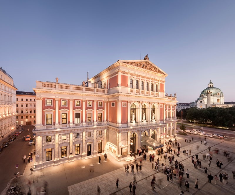 Beleuchteter Musikverein in abendlicher Stimmung und vielen Menschen davor.