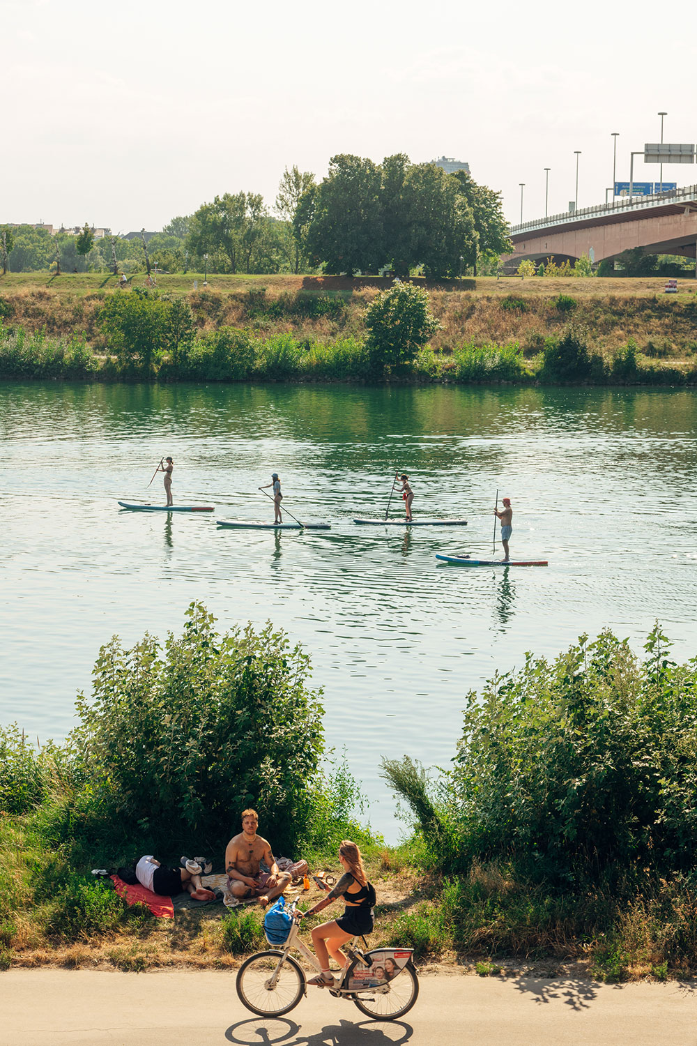 Stand up Paddler im wasser und am Ufer Radfahrer