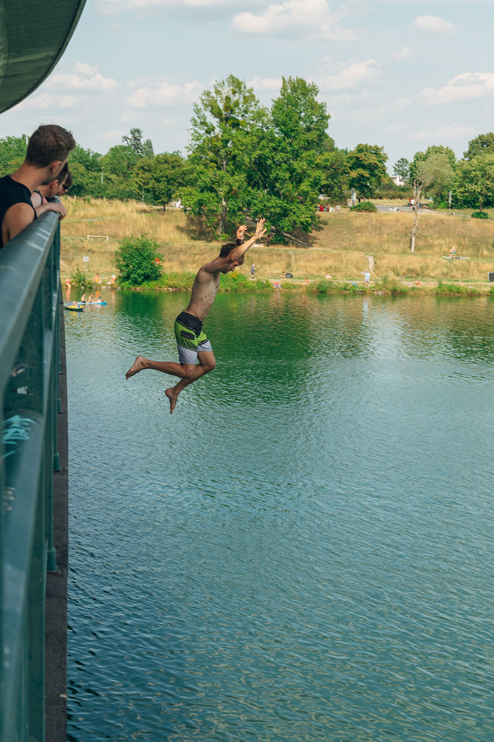 Person springt von einem Geländer ins Wasser