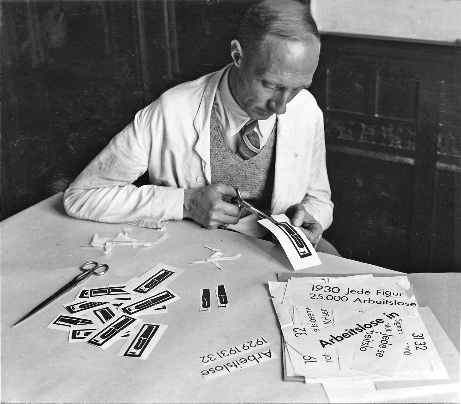  Prozess vom Design der Piktogramme bis zur Produktion der bildstatistischen Tafeln zeigt, Techniker Skuravy schneidet die gedruckten Piktogramme aus