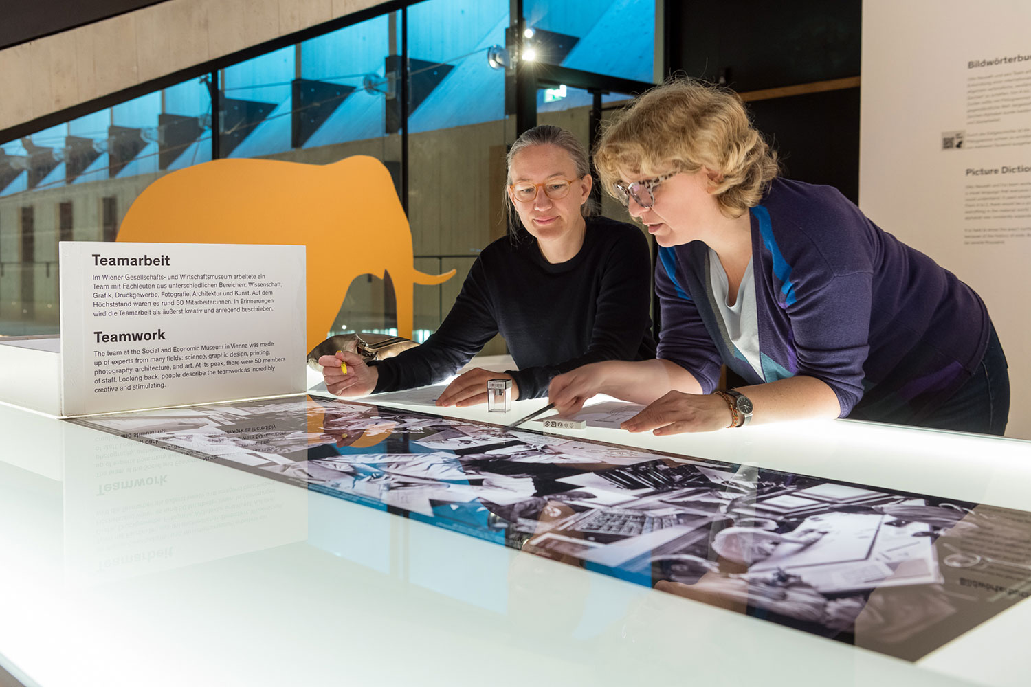 Zwei Personen arbeiten an dem Tisch für Workshops in der Ausstellung 