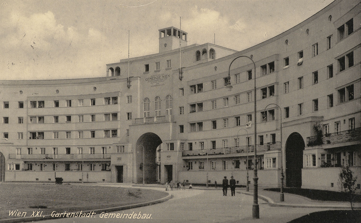 Schwarz-Weiß-Foto des Gemeindebaus mit Vorplatz. 