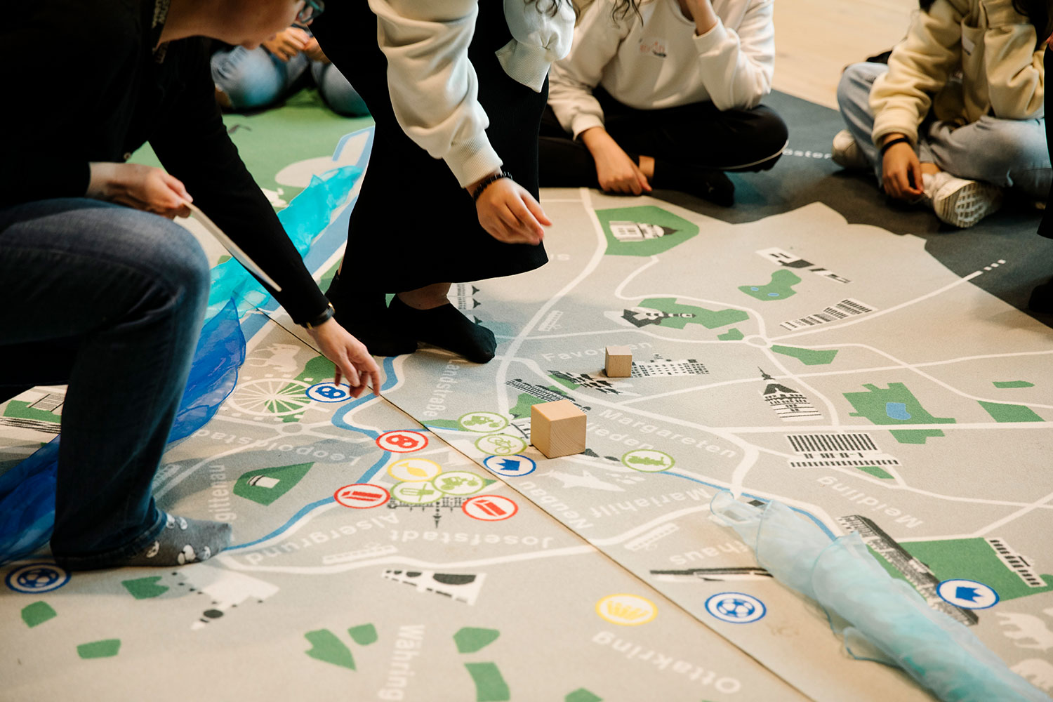 Auf einen Teppich mit dem Stadtplan von Wien bringen die Schüler Gegenstände an.