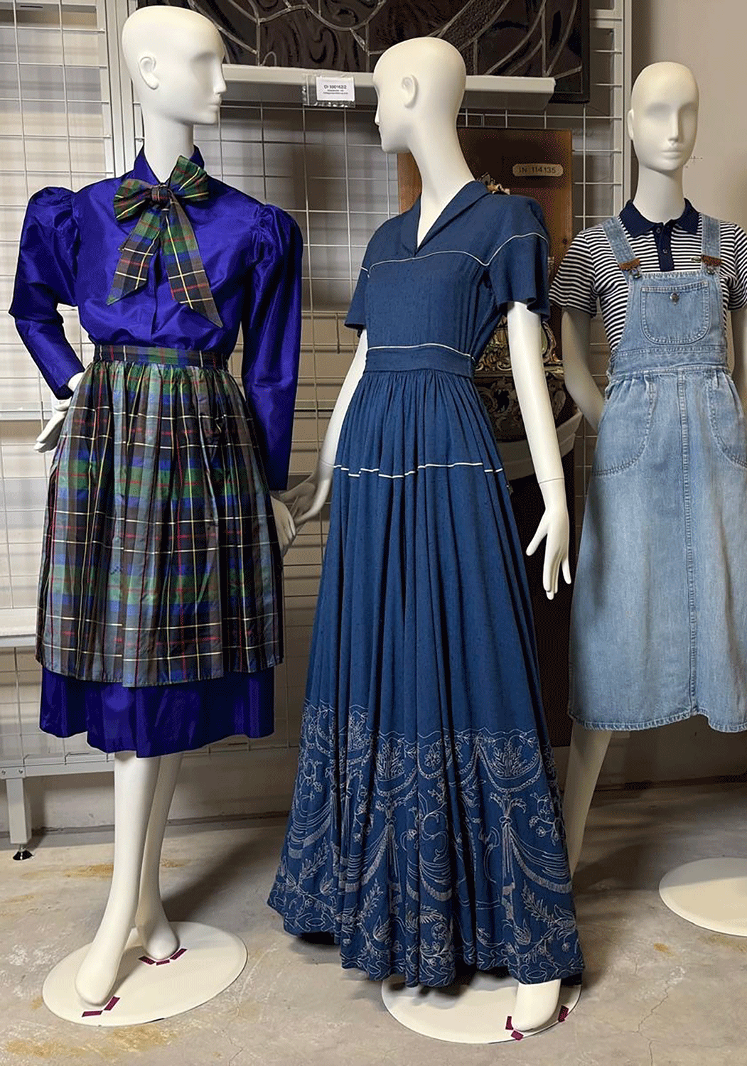 Drei Kleiderpuppen, die jeweils ein blaues Kleid mit unterschiedlichen Schnitten tragen, eines mit karierter Schürze, eines bodenlang und eines hellen Jeanskleides. 