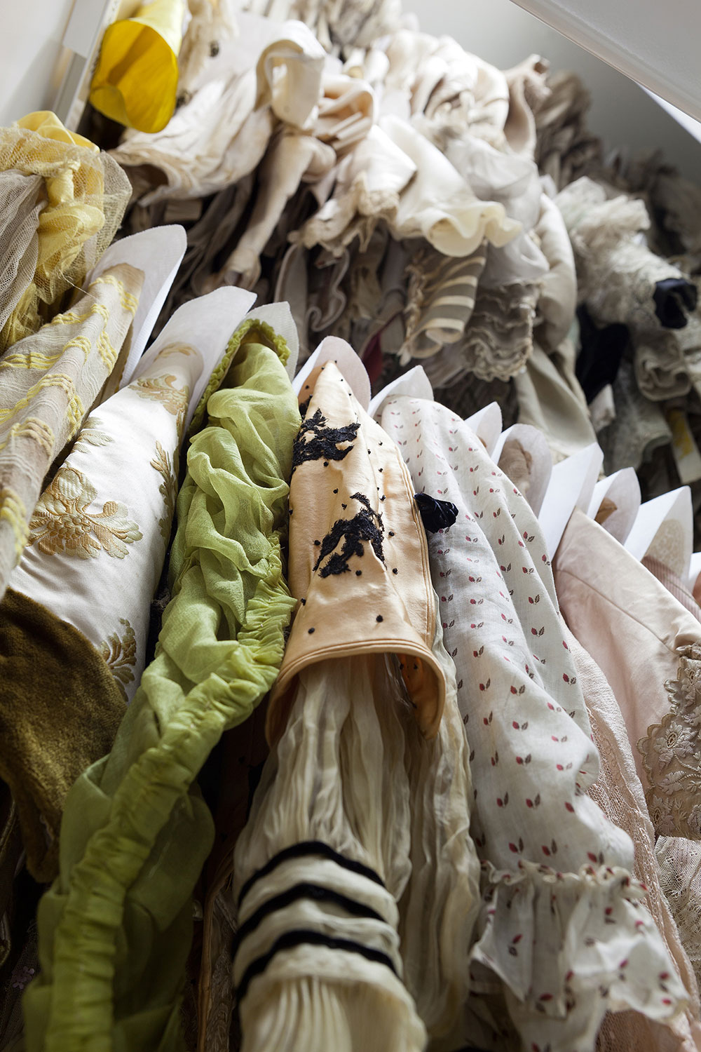 Verschiedene eng gehängte Kleider, die auf zwei Kleiderstangen übereinander angeordnet sind.