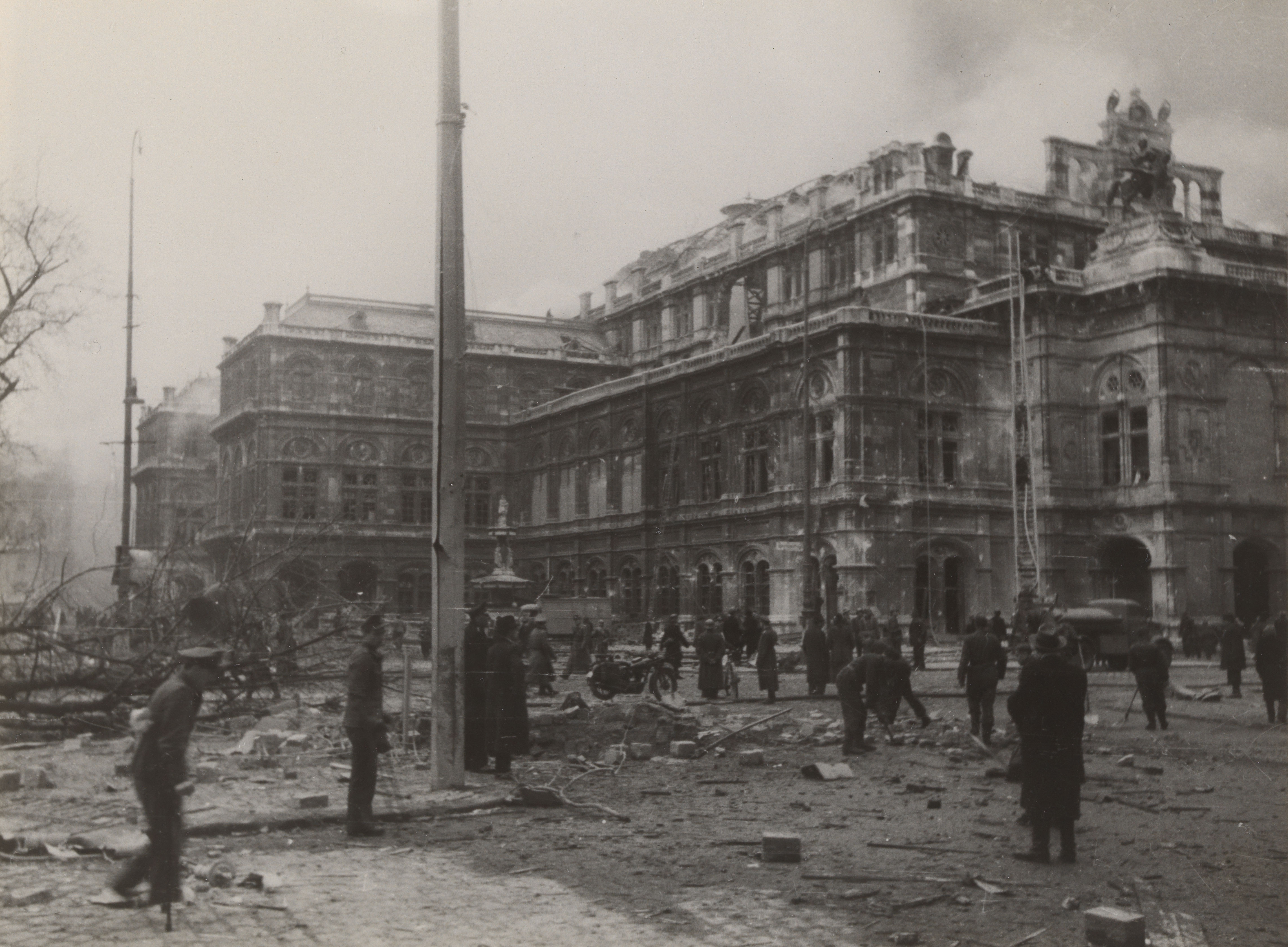 Menschen stehen zwischen Trümmern vor der demolierten Staatsoper