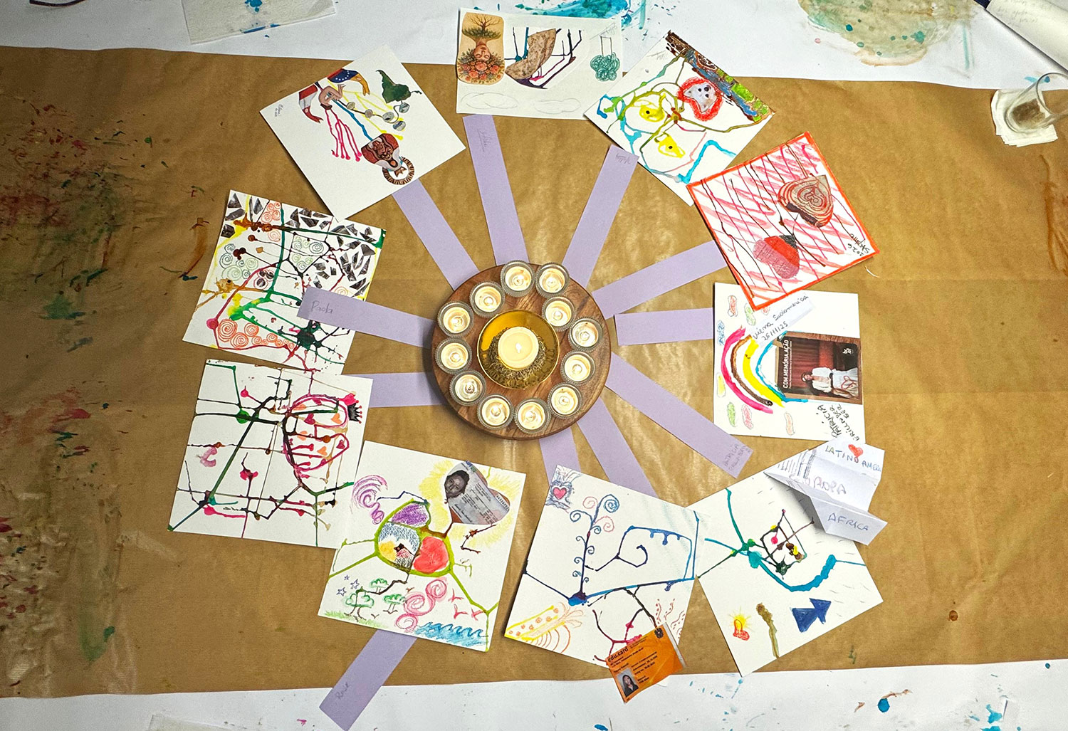 Zeichnungen liegen im Kreis um ein Teller mit Kerzen in der Mitte 