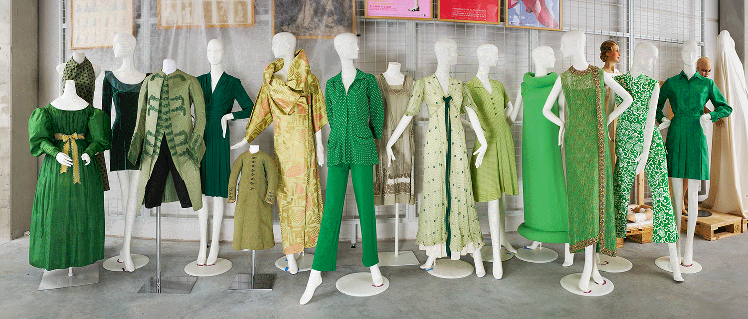 Viele unterschiedliche Modepuppen mit grünen Kleidern aus verschiedenen Jahrhunderten