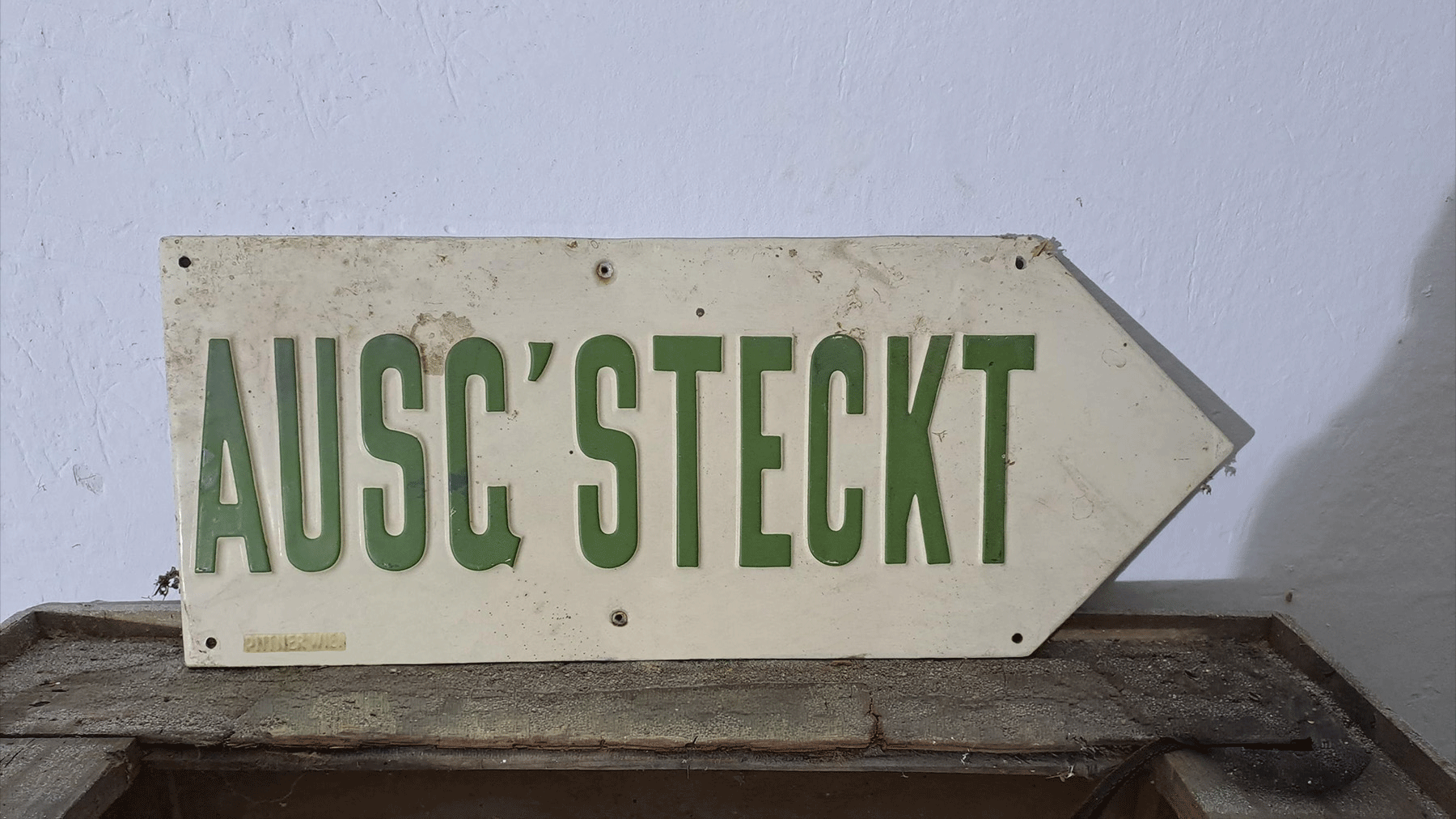 Weißes Schild mit grünem Schriftzug 
