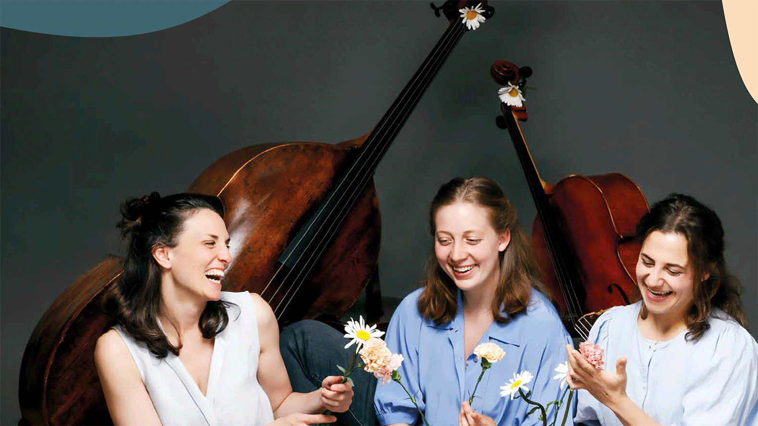 Drei Musikerinnen mit Blumen vor den Intrumenten 